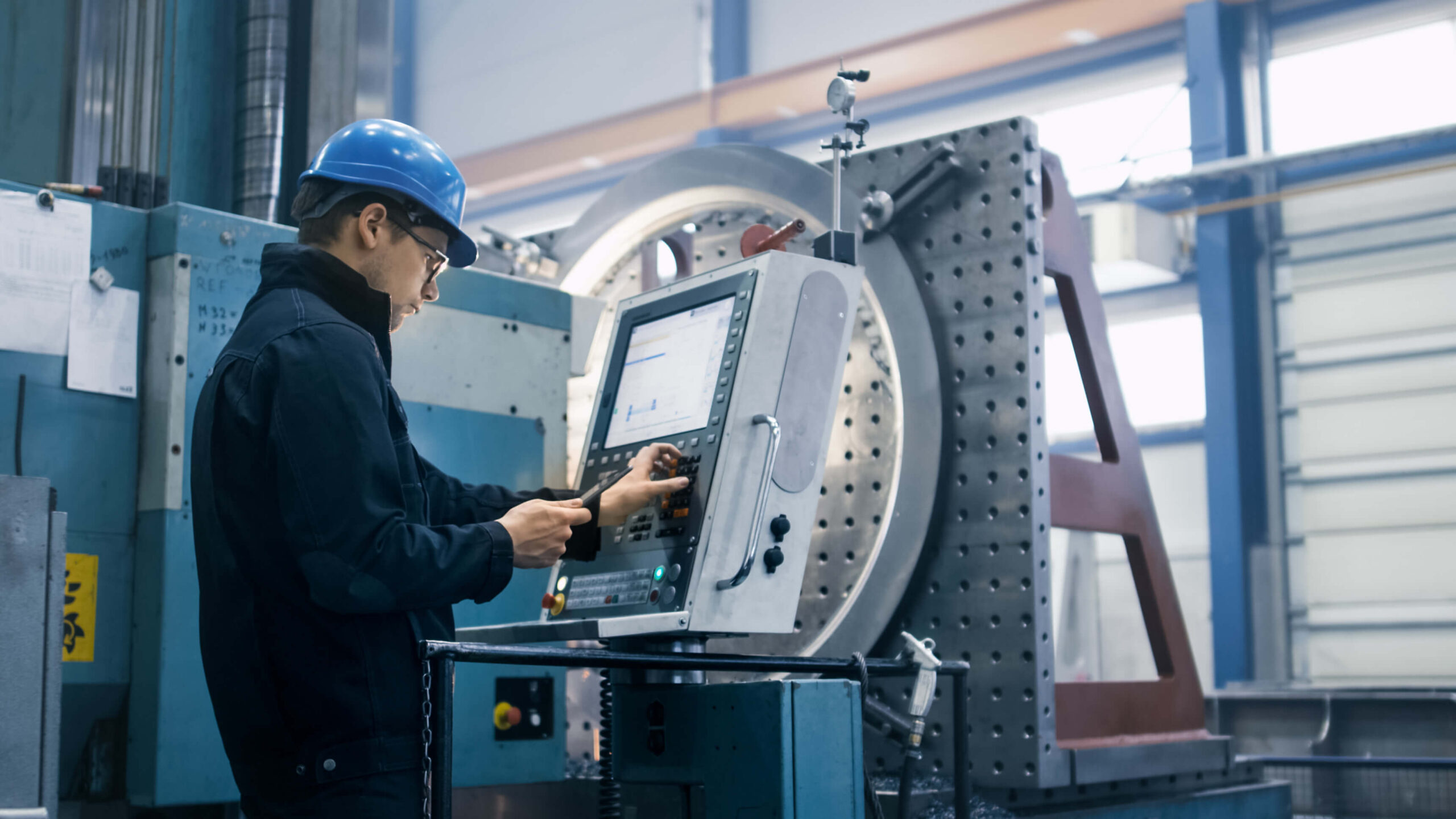 A technician operating a large industrial machine with a digital interface.